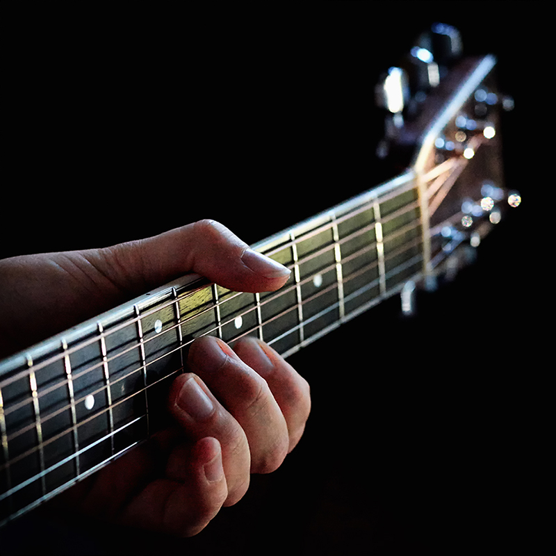 Detail eines Gitarrenhalses und einer Hand